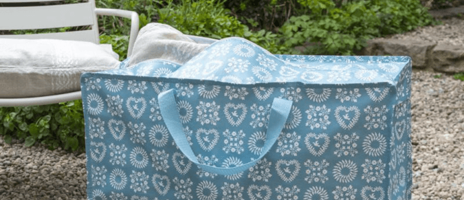 A blue jumbo bag in garden with a cushion poking out of the top