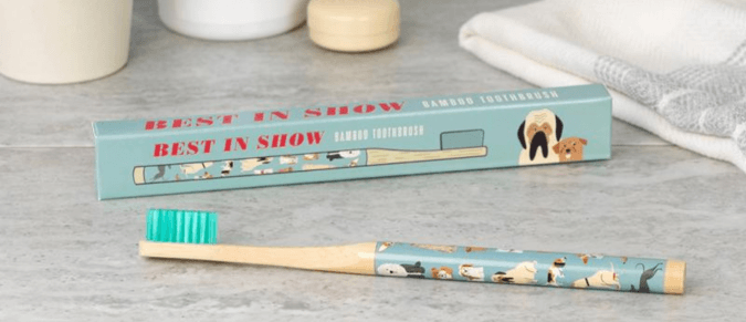 A bamboo toothbrush with a print of dogs on the handle