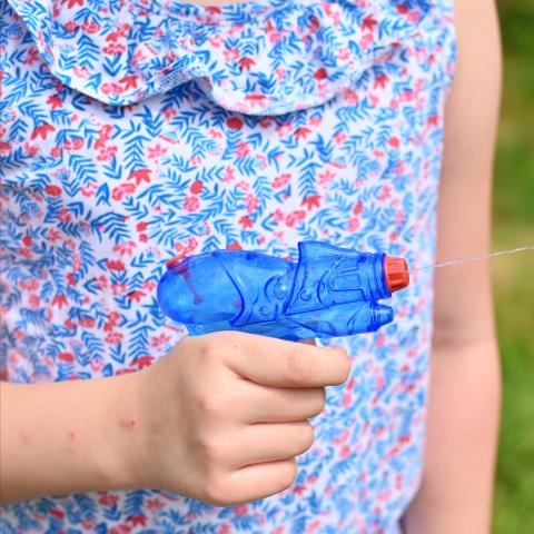 A child's hand holds a small water pistol