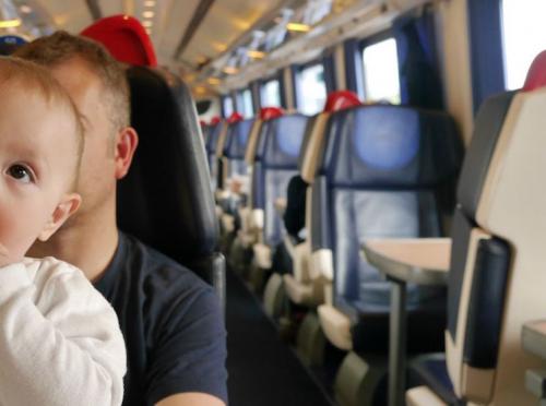 Baby sat contently on a train with his father