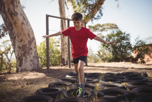 Boy running over tyres in obstacle course