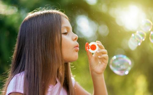 girl blowing bubbles in woods