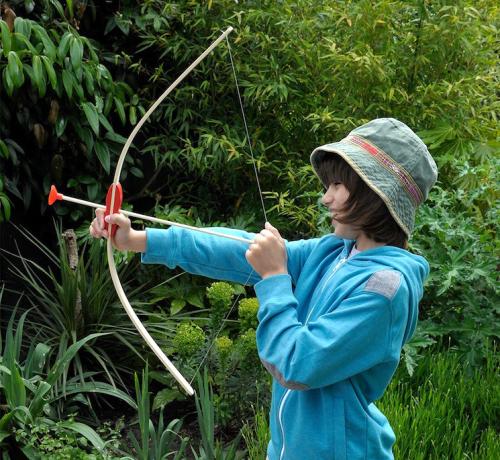 Child aiming bow and arrow set at target