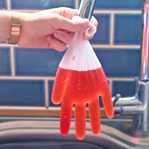 A clear glove is filled with water and red food colouring