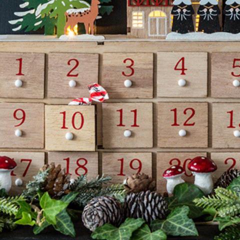 A wrapped sweet pokes out of the drawer of a wooden advent calendar